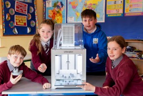 Primary school learners standing around a 3D printer